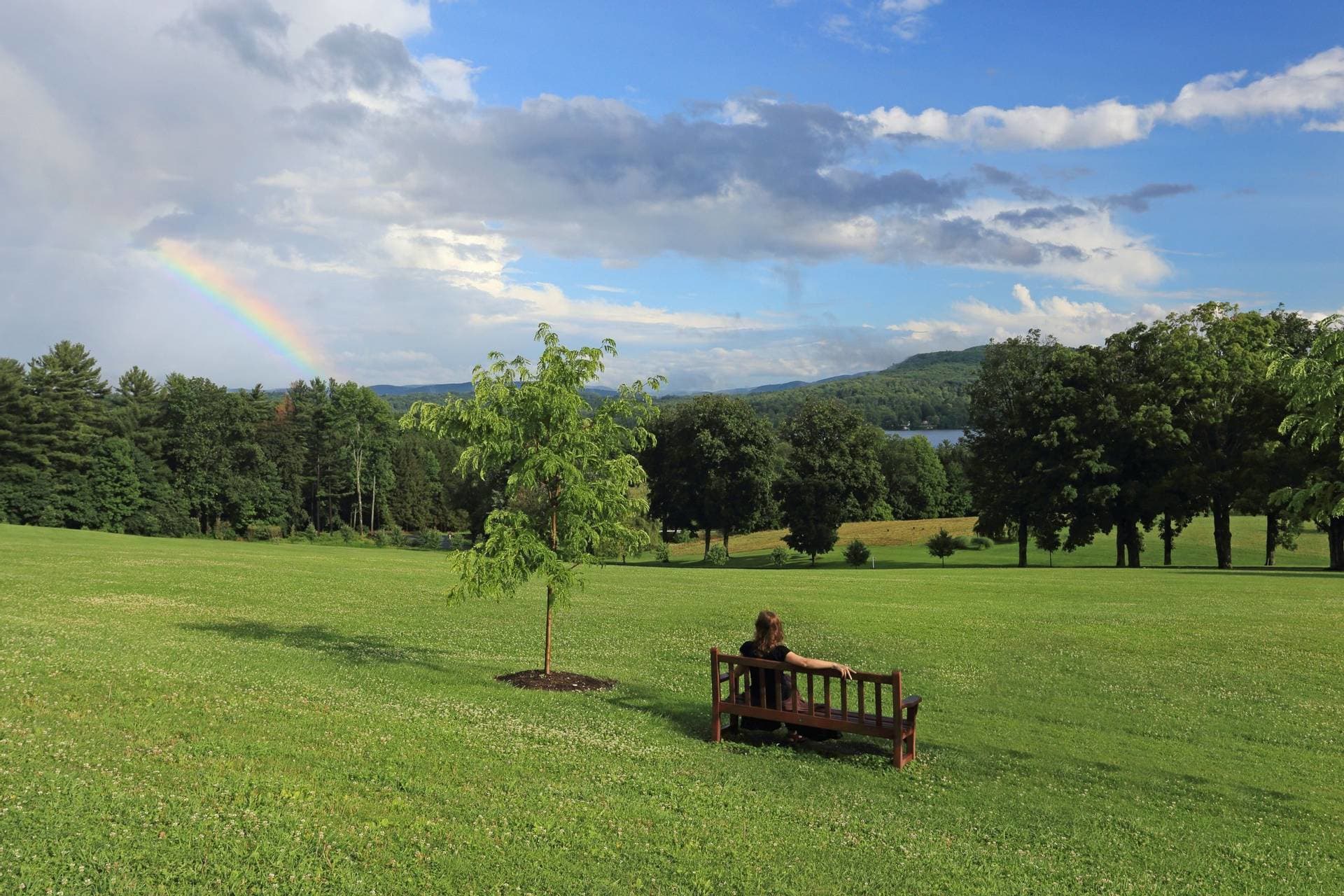 Woman sititng on grounds at Kripalu Center with rainbow overhead